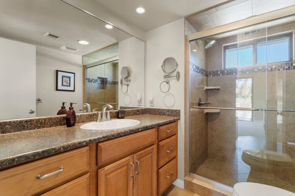 Interior bathroom view of sink with large mirror and glass shower at 40386 Pebble Beach