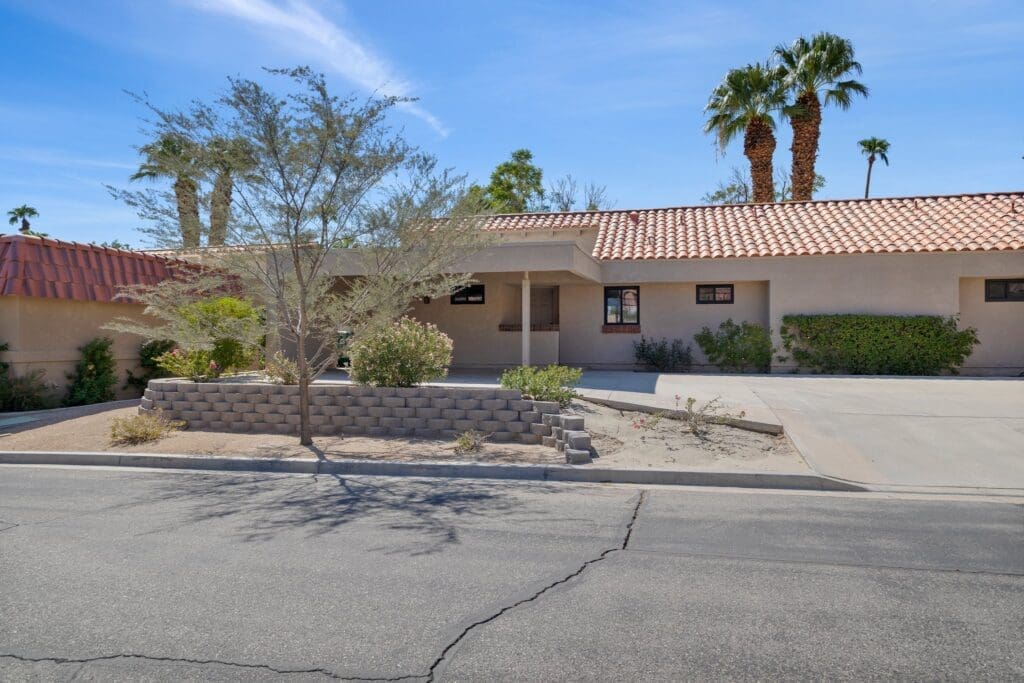 Front exterior view of home with parking area and large tree in front at 40386 Pebble Beach