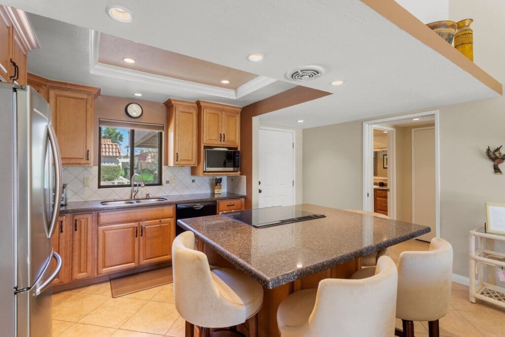 Kitchen and dining area with chairs around island at 40386 Pebble Beach