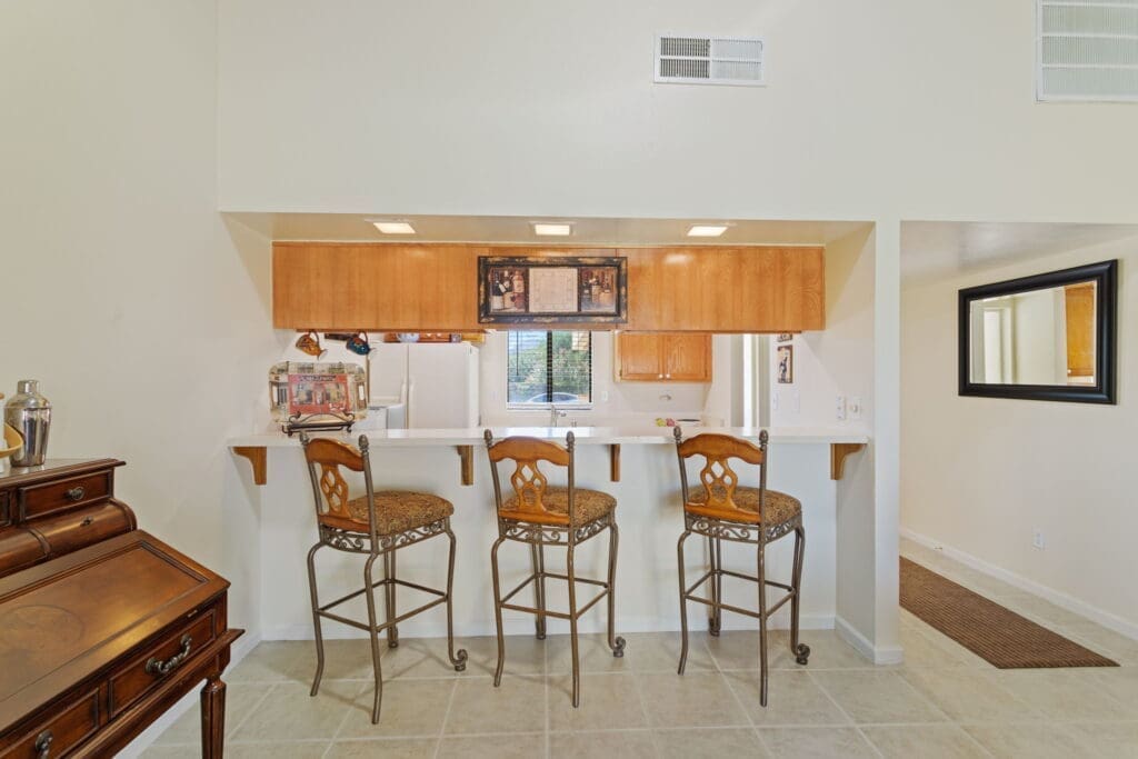 View from living room of kitchen with counters and bar stools at 77042 Pauma Valley Way